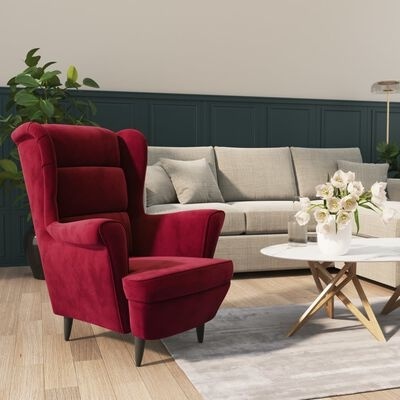 Poltrona vermelha de veludo em sala de estar com sofá cinza e mesa de centro com flores