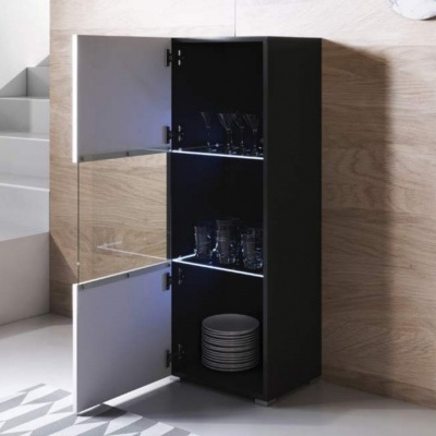 Móvel de cozinha preto com portas brancas, copos e pratos, junto a parede de madeira clara