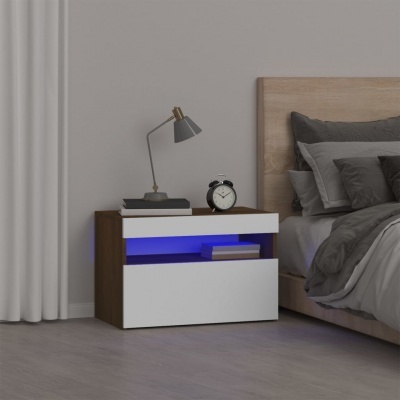 Mesa de cabeceira branca e castanha com luz azul ao lado de cama com roupa cinzenta