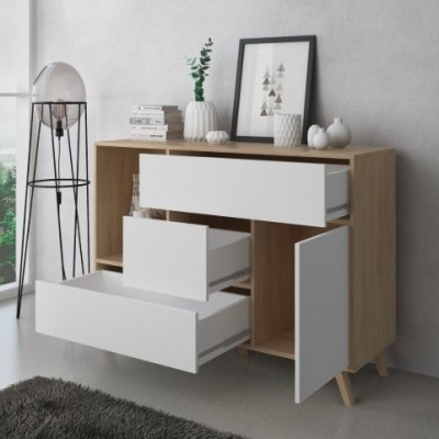 Móvel de arrumação em madeira com gavetas e porta brancas abertas, decorado com vasos e livros, e candeeiro de chão preto ao lado.