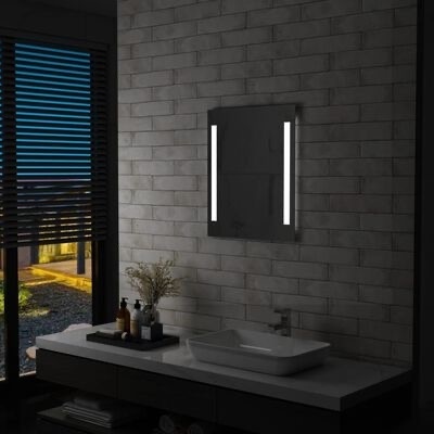 Espelho de parede com luzes LED verticais sobre bancada branca com cuba e acessórios