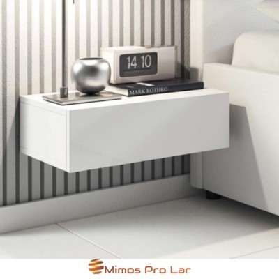 Mesa de cabeceira branca suspensa com relógio digital, livro e objeto prateado