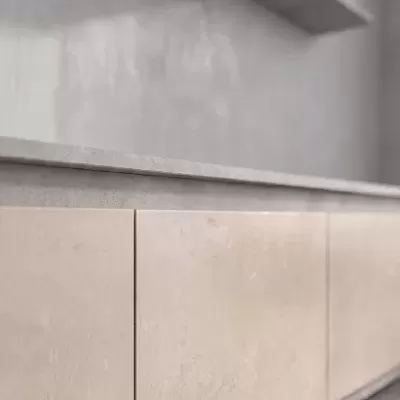 Armário de cozinha bege claro com tampo cinza claro e parede cinza