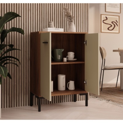 Armário pequeno em madeira castanha escura com portas castanho claro e pernas pretas, numa sala moderna com parede listada e planta