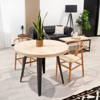 Sala de estar com mesa redonda de madeira clara, duas cadeiras e sofá preto