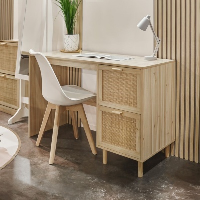 Escrivaninha de madeira clara com gavetas de ratã, cadeira branca e mesa de trabalho com candeeiro