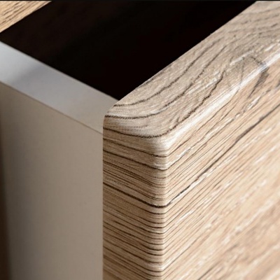 Canto arredondado de móvel de madeira clara com padrão visível