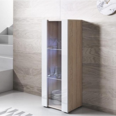 Móvel estreito em madeira clara com portas de vidro e prateleiras com copos e pratos perto de uma escada branca