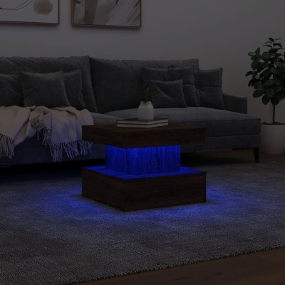 Mesa de centro com iluminação azul em sala com sofá cinzento e planta.