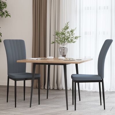 Conjunto de jantar com mesa em madeira clara e duas cadeiras azul-escuras numa sala com cortinas e chão xadrez cinzento