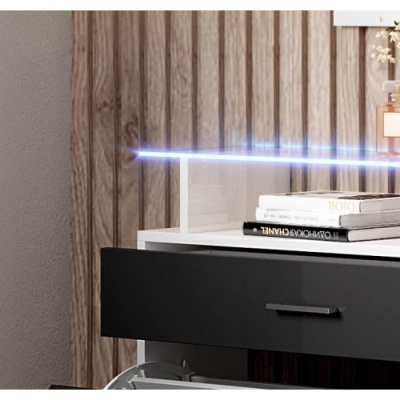 Mesa branca com gaveta preta aberta e livros em cima junto a parede de madeira.