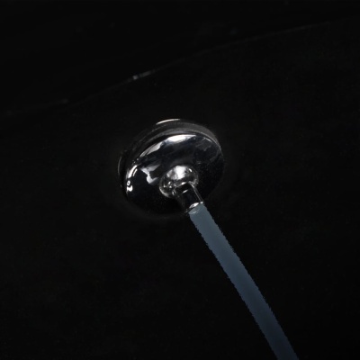 Puxador metálico prateado redondo com cabo cinzento em superfície preta.