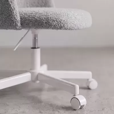 Cadeira de escritório cinza com base branca e rodas sobre chão de cimento.