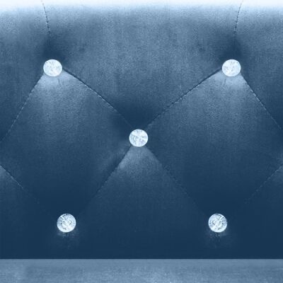 Encosto de sofá azul escuro com botões decorativos brilhantes em padrão acolchoado