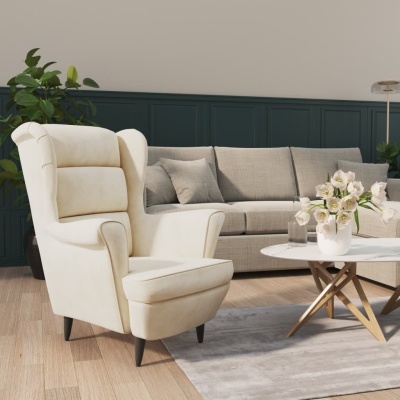 Sala com poltrona creme, sofá cinza, mesa de centro branca com flores e planta verde.