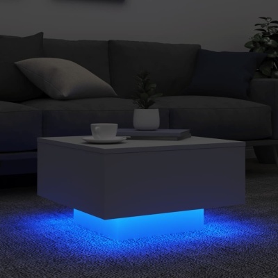 Mesa de centro branca iluminada com LED azul numa sala de estar com sofá cinzento e almofadas.