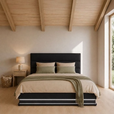 Cama de casal preta com roupa de cama bege e verde, mesa de cabeceira com candeeiro e cesta ao lado