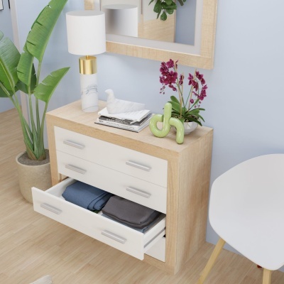 Cómoda de madeira clara com gavetas brancas e decoração com vaso de flores e candeeiro