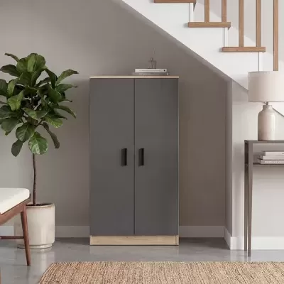 Cómoda cinzenta com base de madeira, planta em vaso e mesa com candeeiro sob escadas