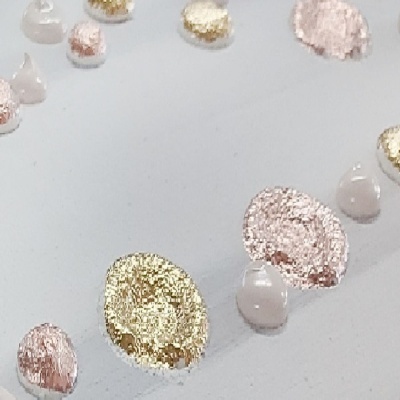 Gotas e manchas metálicas dourado e rosa com gotas brancas sobre fundo branco
