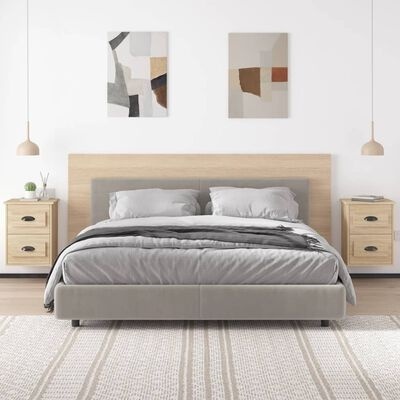 Cama cinzenta com cabeceira em madeira clara entre duas mesas de cabeceira suspensas em quarto minimalista com quadros abstratos na parede