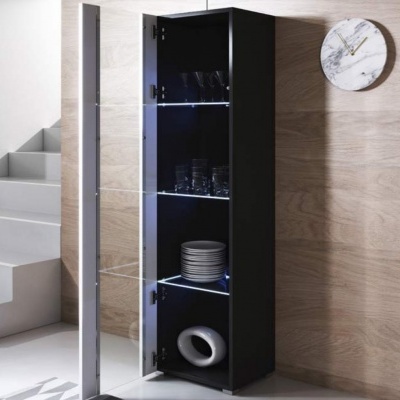 Móvel de arrumação preto com porta de vidro espelhado com pratos, copos e peça decorativa em interior com parede de madeira e relógio