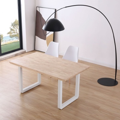 Mesa de madeira clara com duas cadeiras brancas, candeeiro de pé preto e quadro abstrato junto a janela