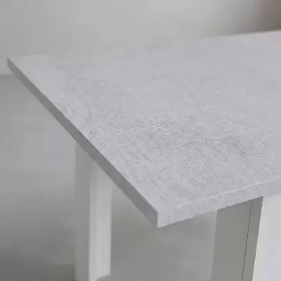 Mesa cinzenta com pernas brancas sobre chão cinzento