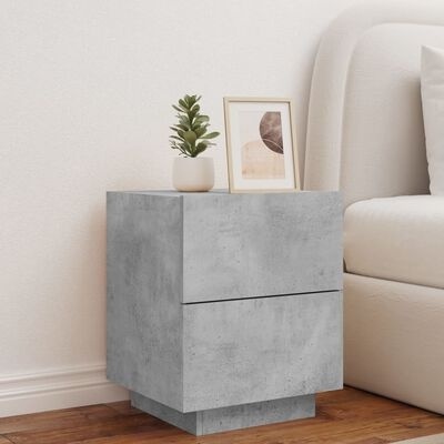 Mesa de cabeceira cinzenta em estilo moderno com planta e quadro em cima, ao lado de sofá creme