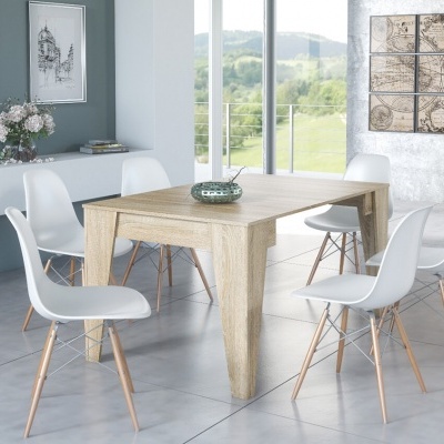 Mesa de jantar de madeira clara com seis cadeiras brancas em sala decorada, chão cinzento, quadros e janela grande com vista verde