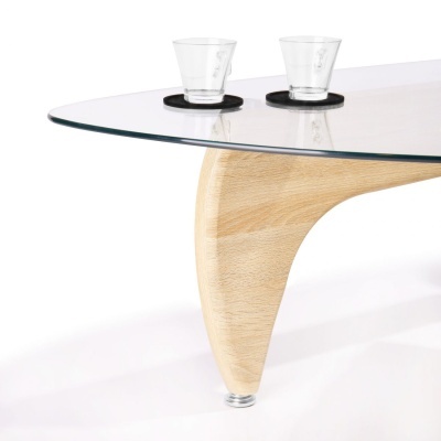 Mesa com tampo de vidro e pernas de madeira clara, dois copos transparentes em descansos pretos