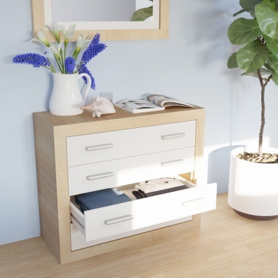 Cômoda de madeira clara com gavetas brancas e decoração com jarro de flores, concha e livro