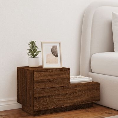 Mesa de cabeceira de madeira com planta e quadro ao lado de cama branca