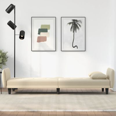 Sofá-cama creme com pernas pretas, dois quadros coloridos e luminária preta numa sala branca