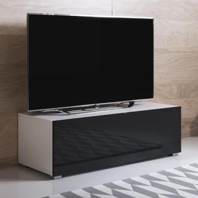 Móvel branco com porta preta brilhante e televisão em cima, em ambiente interior com parede de madeira clara e tapete cinza e branco.