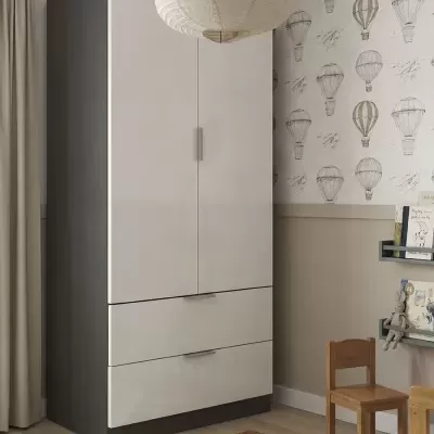Guarda-roupa branco e cinza numa sala infantil com papel de parede de balões, tapete xadrez, cadeira de madeira e prateleiras com livros e brinquedos