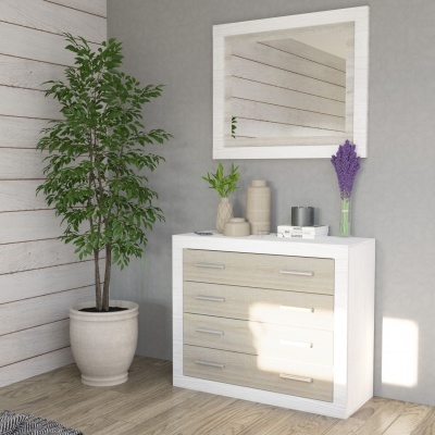 Cómoda branca com gavetas de madeira clara decorada com vasos e flores, espelho branco na parede cinzenta e planta em vaso ao lado