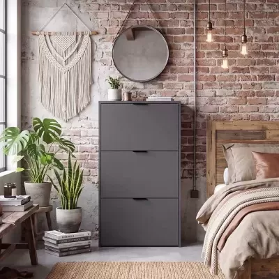 Quarto com cómoda cinza, espelho redondo, tapeçaria macramé, plantas em vasos, candeeiros suspensos e cama de madeira