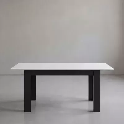 Mesa de jantar retangular branca com pernas pretas num espaço interior minimalista.