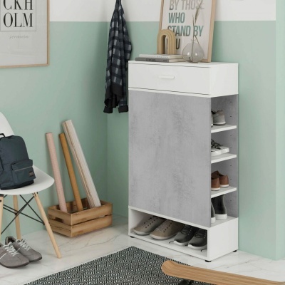 Móvel branco para sapatos com porta cinzenta e sapatos organizados, numa sala com parede verde, tapete cinzento e cadeira branca