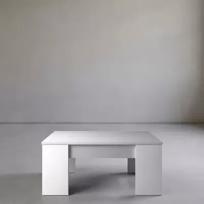 Mesa quadrada branca minimalista num espaço interior cinzento