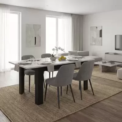Mesa de jantar com quatro cadeiras cinzentas sobre tapete bege em sala com chão de madeira e paredes brancas.