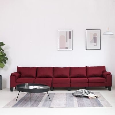 Sofá vermelho escuro de seis lugares num ambiente moderno com mesa de centro preta e decoração minimalista.