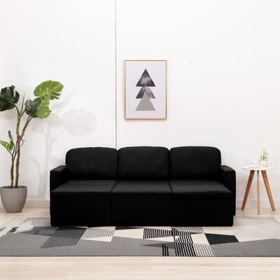 Sofá preto de três lugares numa sala minimalista com planta, mesa de apoio, tapete e quadro na parede.