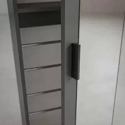Porta de armário cinzenta com puxador preto e prateleira metálica interior