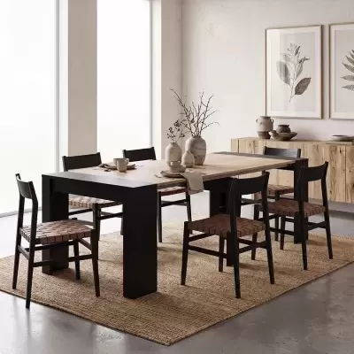 Mesa de jantar com seis cadeiras, vasos cerâmicos e decoração minimalista junto a parede com quadros botânicos