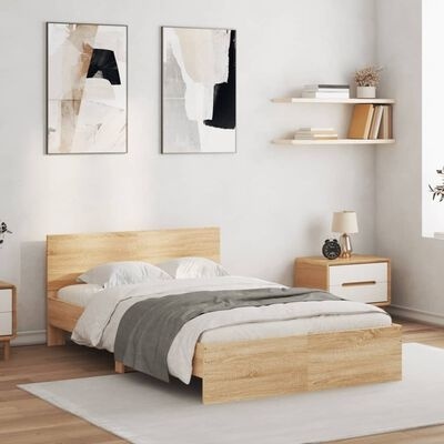 Quarto moderno com cama de madeira clara, roupa de cama branca e cinzenta, tapete, mesas de cabeceira com candeeiro e relógio, prateleiras e pinturas abstratas
