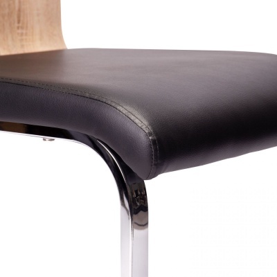 Cadeira com assento preto estofado, estrutura metálica cromada e encosto em madeira clara