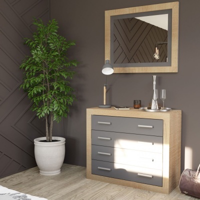 Cómoda com gavetas em madeira clara, cinza e branco, com espelho, luminária, decorações e planta num vaso branco.