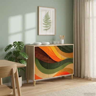 Aparador de madeira com padrão colorido abstrato nas portas, utensílios de cozinha no tampo, parede verde com quadro e cortinas bege.